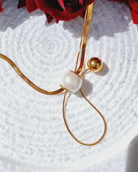 Gold snake chain necklace with a large white pearl and small gold bead