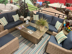 Outdoor sectional with neutral color frame, blue cushions, and fire pit.
