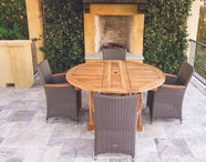 A small, round drop leaf table surrounded by sling dining chairs.