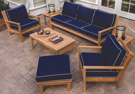 Outdoor teak seating set with sofa, two chairs, coffee table, and end table.