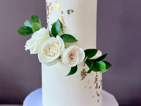 wedding cake with gold leaf and white roses
