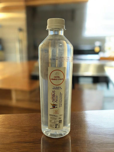 Clear glass water bottle with minimalist label on a wooden table.
