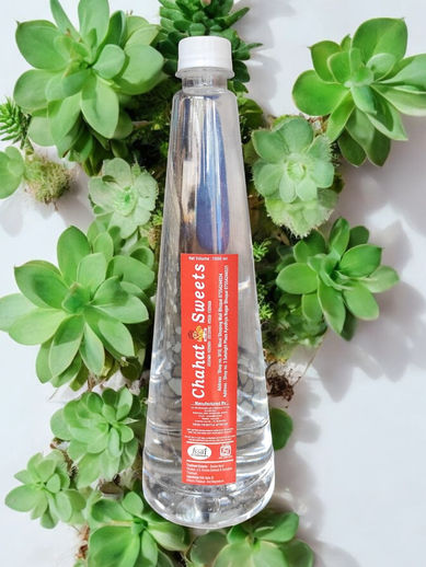 Clear bottle of "Chabeli La Savita" surrounded by green succulents.