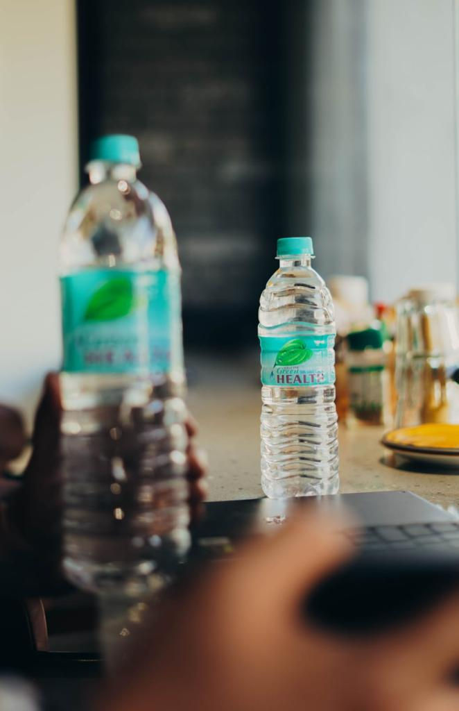 Two Green Health branded plastic water bottles on a table surface.