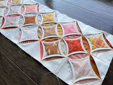 A few rows of in- progress cathedral windows quilt top.