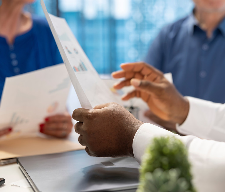 man holding paper paper with information with 2 people unfocused in the background