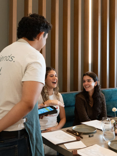 LB Eatery & Wine server talking to customers seated at the table