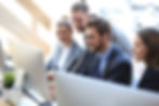 Four workers gathered around a computer, professional development
