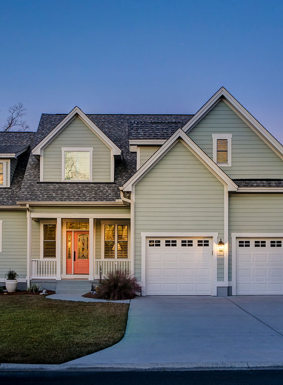 beautiful home with two car garage and light green siding.