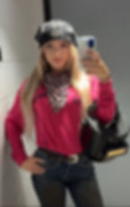 Woman in a white FR welding jacket with a pink headband, smiling and winking.