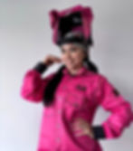 Woman wearing a pink FR welding shirt and helmet, smiling and posing.