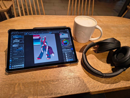 Een tablet met hierop een schets van 2 dames. hiernaast een kop chai latte en een hoofdtelefoon.