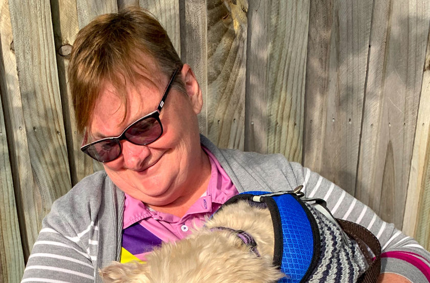 Woman with glasses hugging a dog; dog licking her face. Nanna Jen’s Services