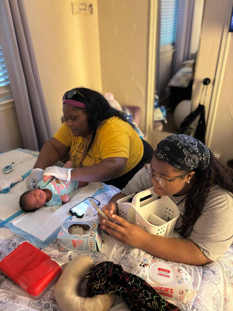 Two women tending to a newborn baby on a bed
