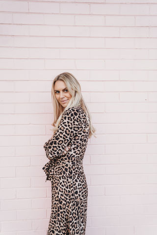 Woman standing by a pink wall, girl boss vibes