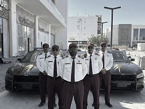 فريق حراسات أمنية محترف من شركة تاسك فورس 1 يرتدون الزي الرسمي ويقفون أمام دوريات أمنية مجهزة لتأمين المنشآت والمواقع التجاري