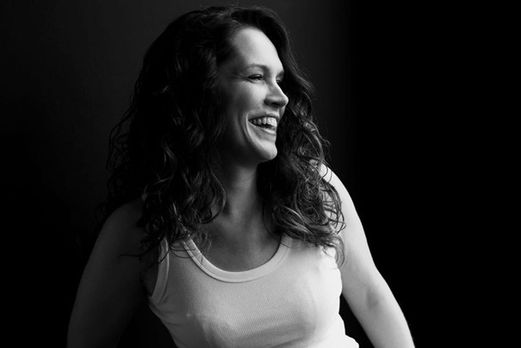 Zwart-wit portret van Erika, lachend en opzij kijkend in witte top
