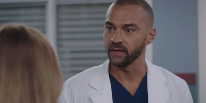 Jackson Avery's return to Grey-Sloan Memorial, looking serious in his scrubs and lab coat amidst looming Grey's Anatomy drama.