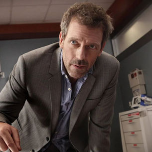 El Dr. Gregory House inclinado hacia adelante, examinando algo intensamente, personificando su brillantez diagnóstica y la impactante entrega de House M.D. quotes.