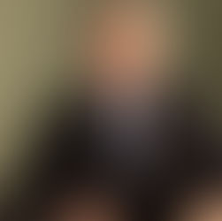 Martin Clunes as Dr. Martin Ellingham sits at his surgery desk wearing a sharp suit and tie with a serious expression in the hit series Doc Martin.