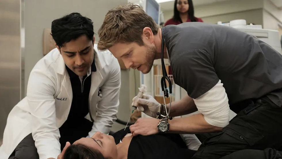 Conrad Hawkins and Devon Pravesh perform an emergency medical procedure on a patient in a hallway scene from the TV show The Resident.