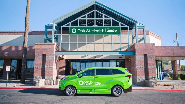 Green Oak Street Health vehicle parked in front of an Oak Street Health clinic, showcasing convenient access to healthcare services.