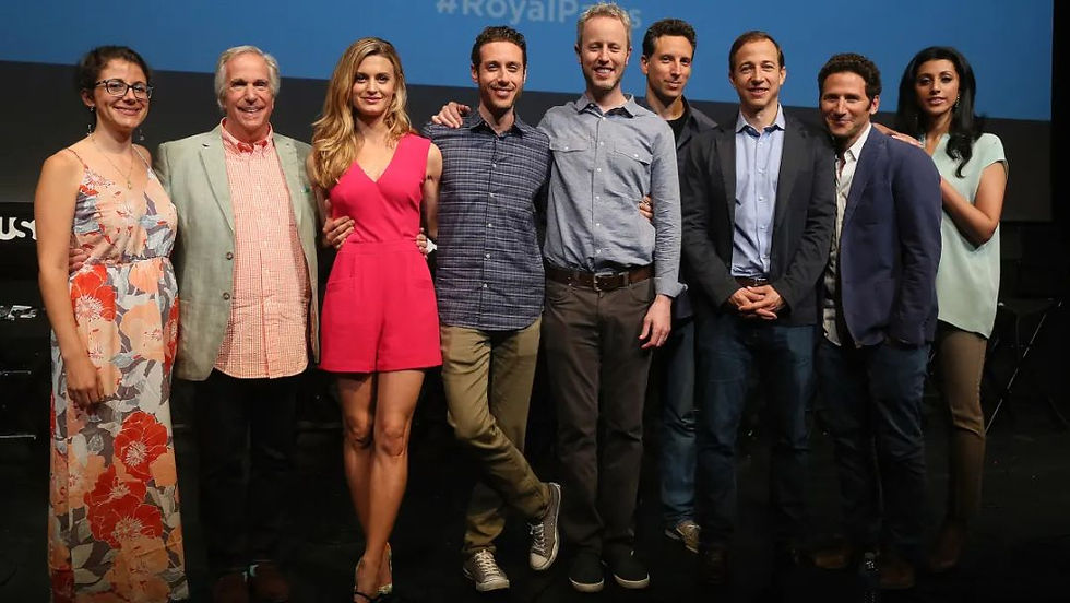 El elenco de Royal Pains junto en el escenario, una alegre reunión que insinúa la emoción por el reinicio de Royal Pains.