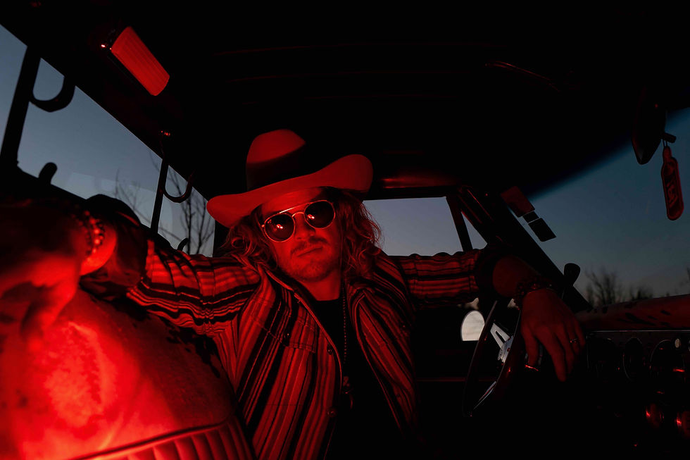 Kyle Daniel sits in a dimly let truck and looks at the camera with his sunglasses on