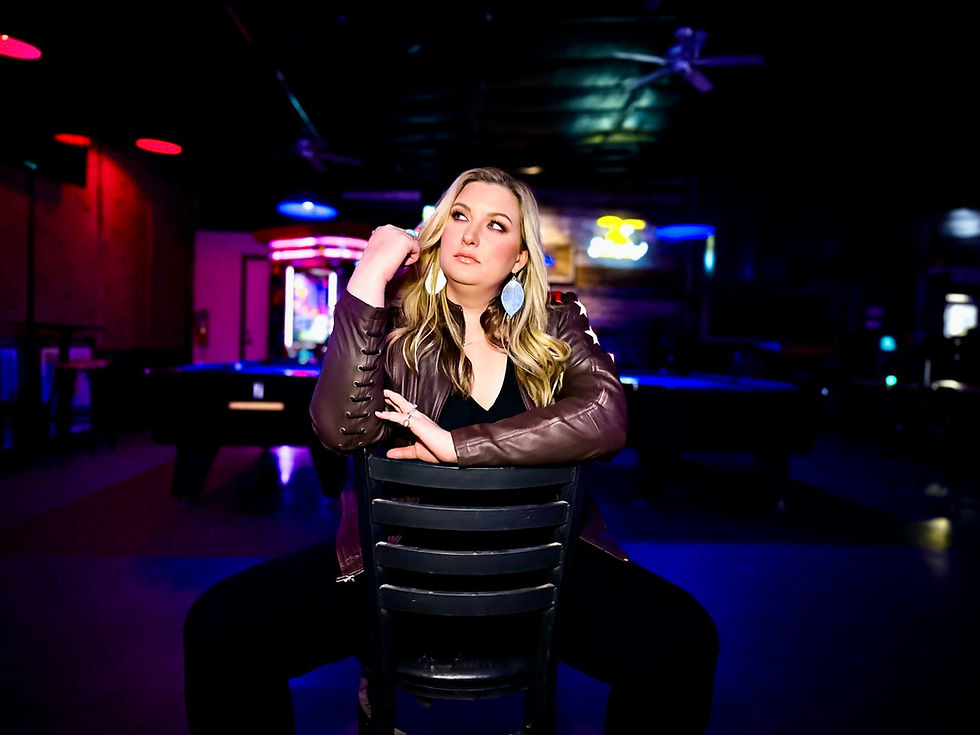 Ash Taylor sits on a backwards chair in a dimly lit bar and looks off into the distance