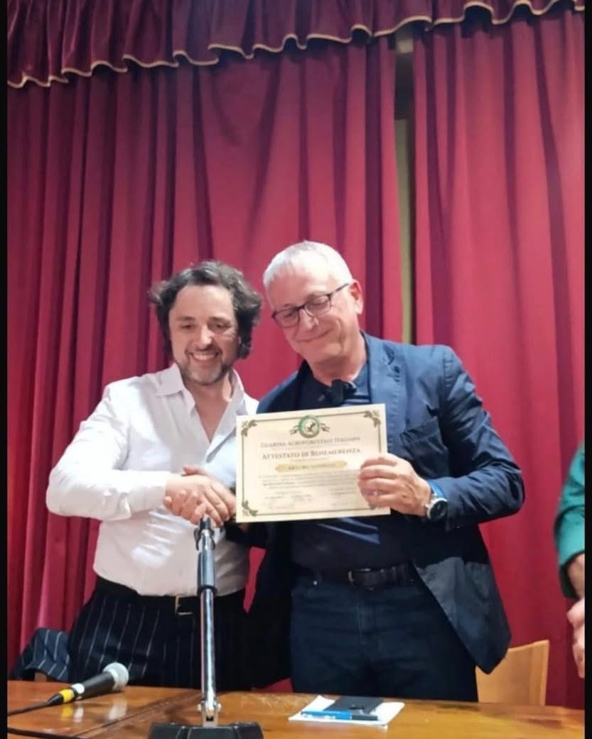 Due uomini sorridenti con un attestato a Sarno.