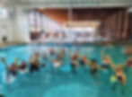 Group of smiling members in the therapy pool doing an aquatic fitness class at AFC Feasterville