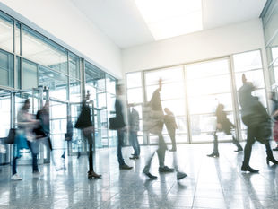 Blurred image of business professionals walking through an office, symbolising rushing into AI decisions.