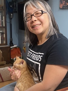 Mina holding baby orange tabby kitten.
