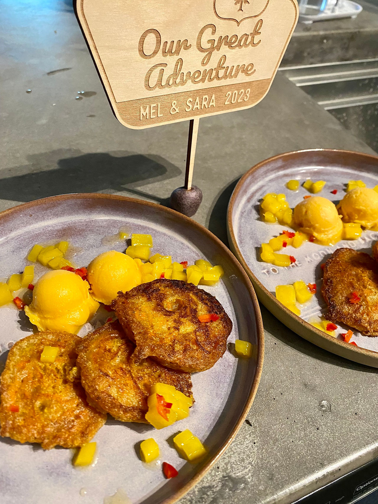 Cardemom Pancakes cooked on silver plates next to a wooden sign that reads Out Great Adventure.