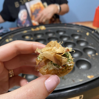 a photo of takoyaki, holding by a woman's hand