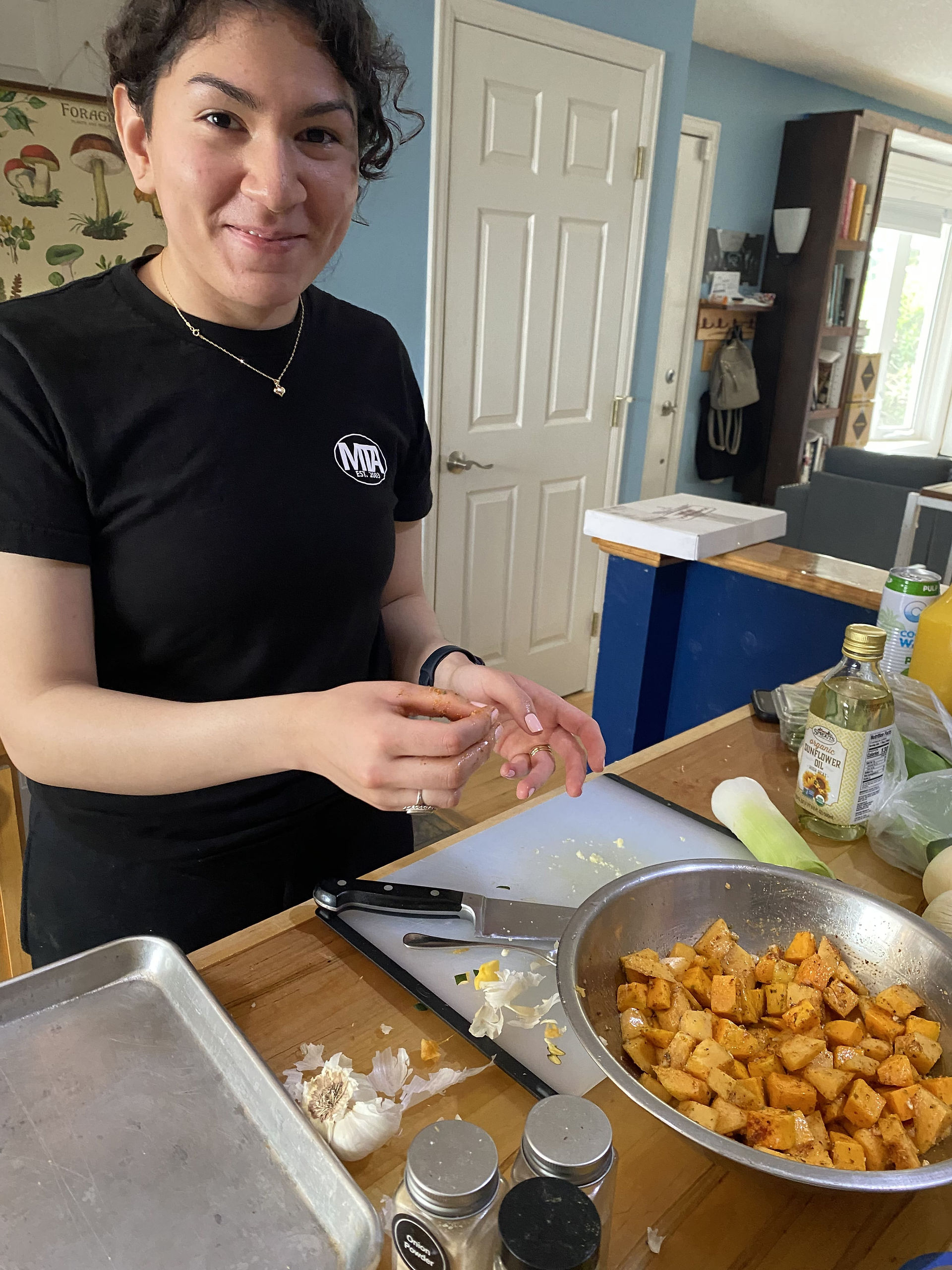 A young indigenous woman in black T-shirt, preparing a meal by a kitchen island, smiling and ready to cook