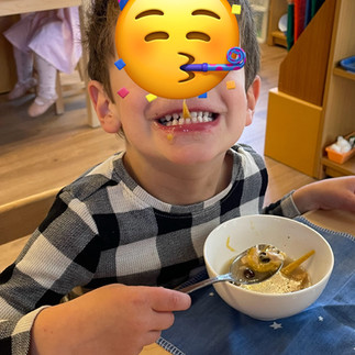 A 3 year old boy (face hidden by a sticker) showing his teeth with cheese in between