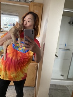 Orange tabby kitten behind held and kissing a woman's face.