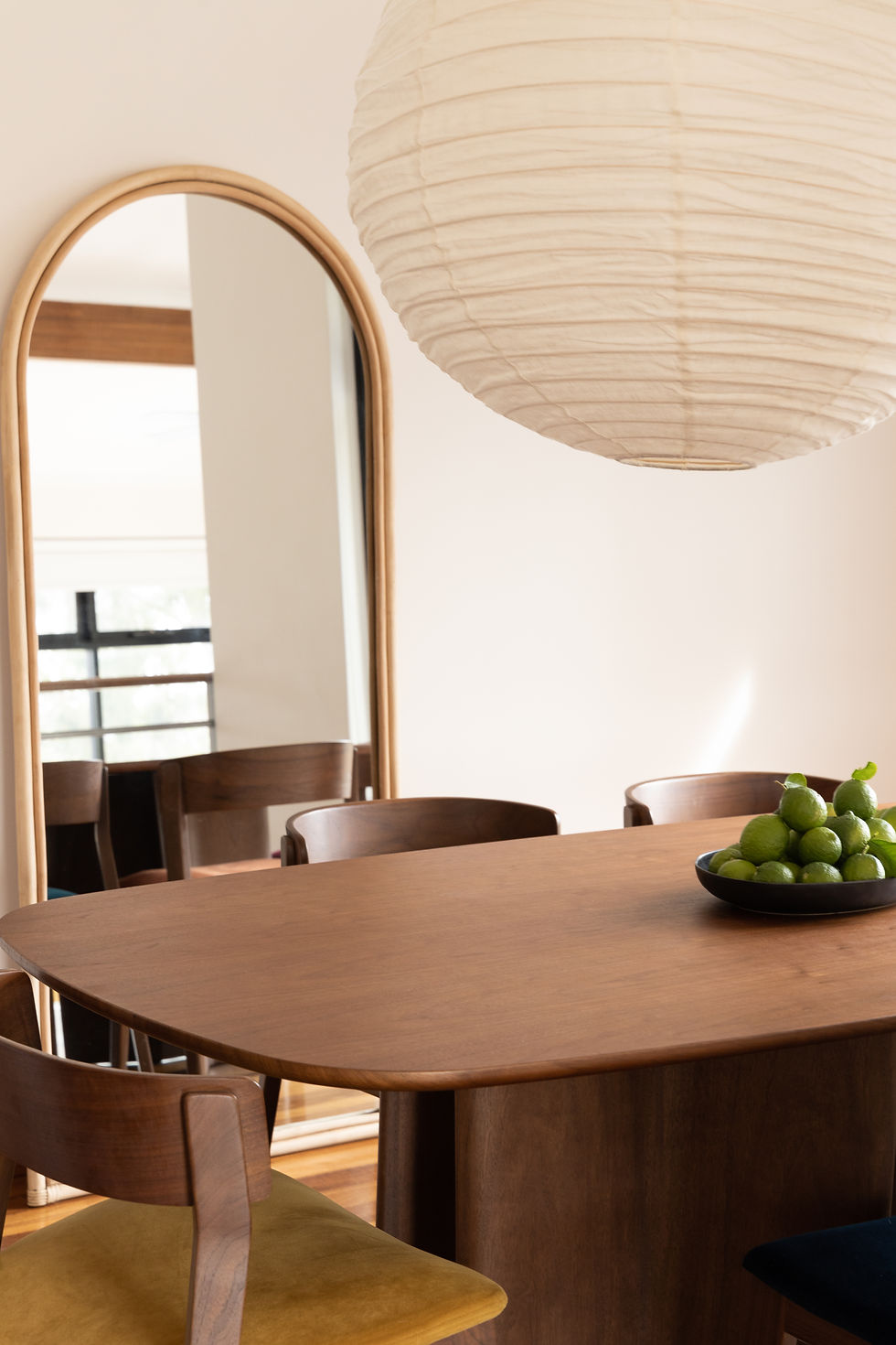Archie rattan arched mirror styled in dining room with linen round pendant light and mid century modern timber dining table