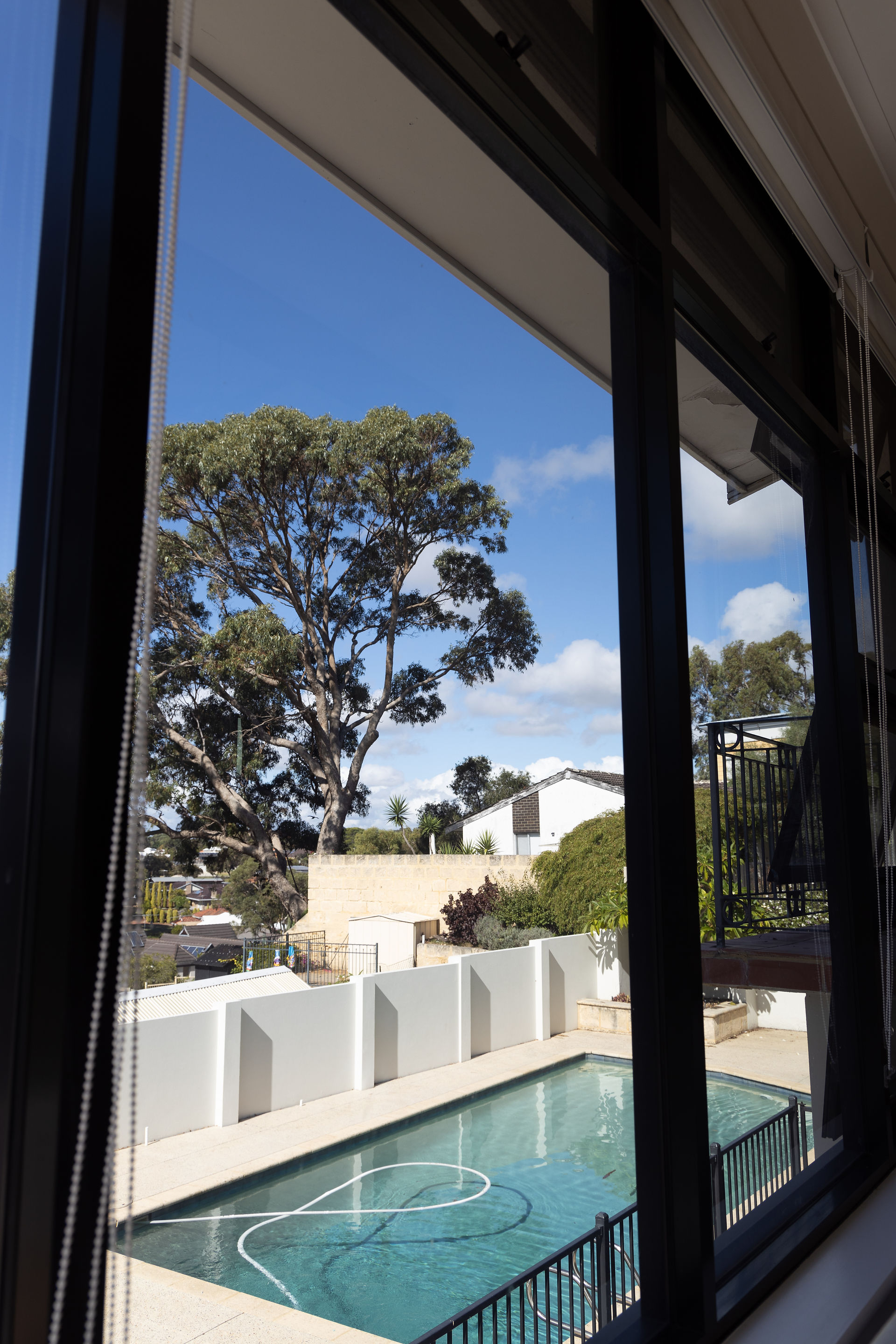Living room view of pool against backdrop of hilltop Perth suburb 