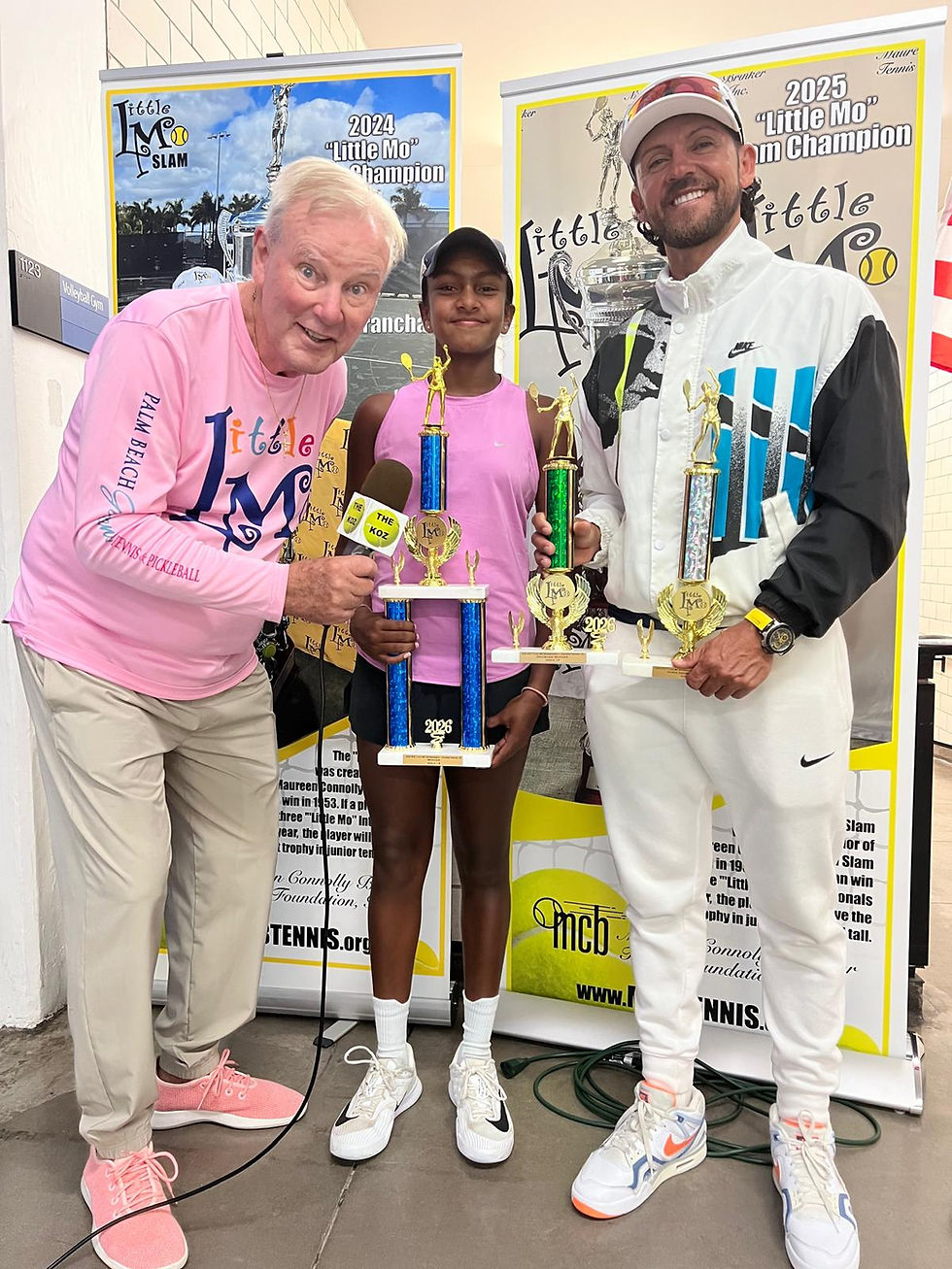 April Thirumalaiyandi and her coach Reynaldo Garcia (right) collect the winning trophies from a league organizer of the Little Mo Tennis Competition
