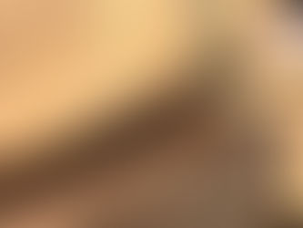 Large oak beams stacked and spray-marked with red symbols, showing end grain checking and cracks, stored in a timber yard under a clear blue sky.