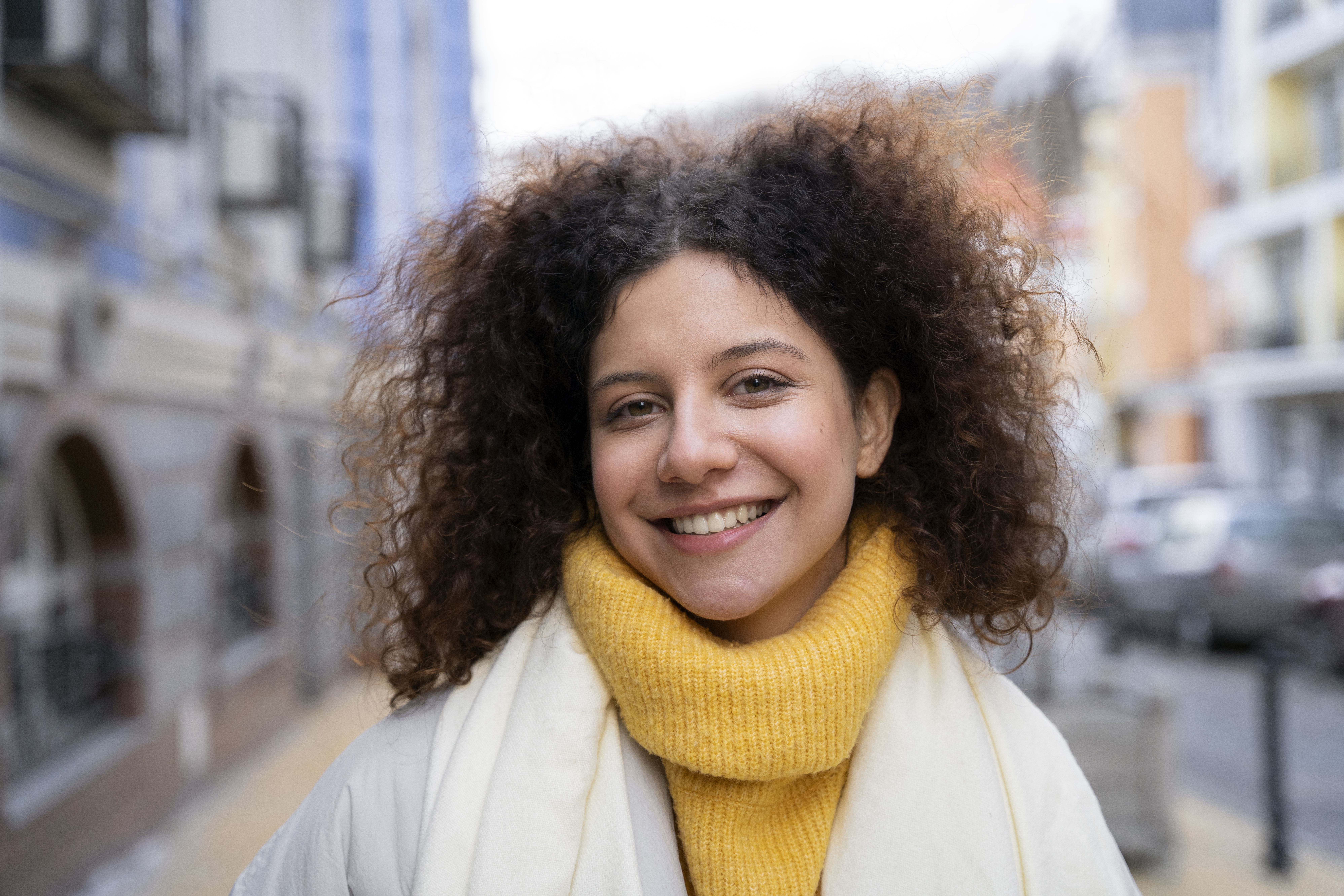 Smiling woman with curly hair wearing a yellow scarf