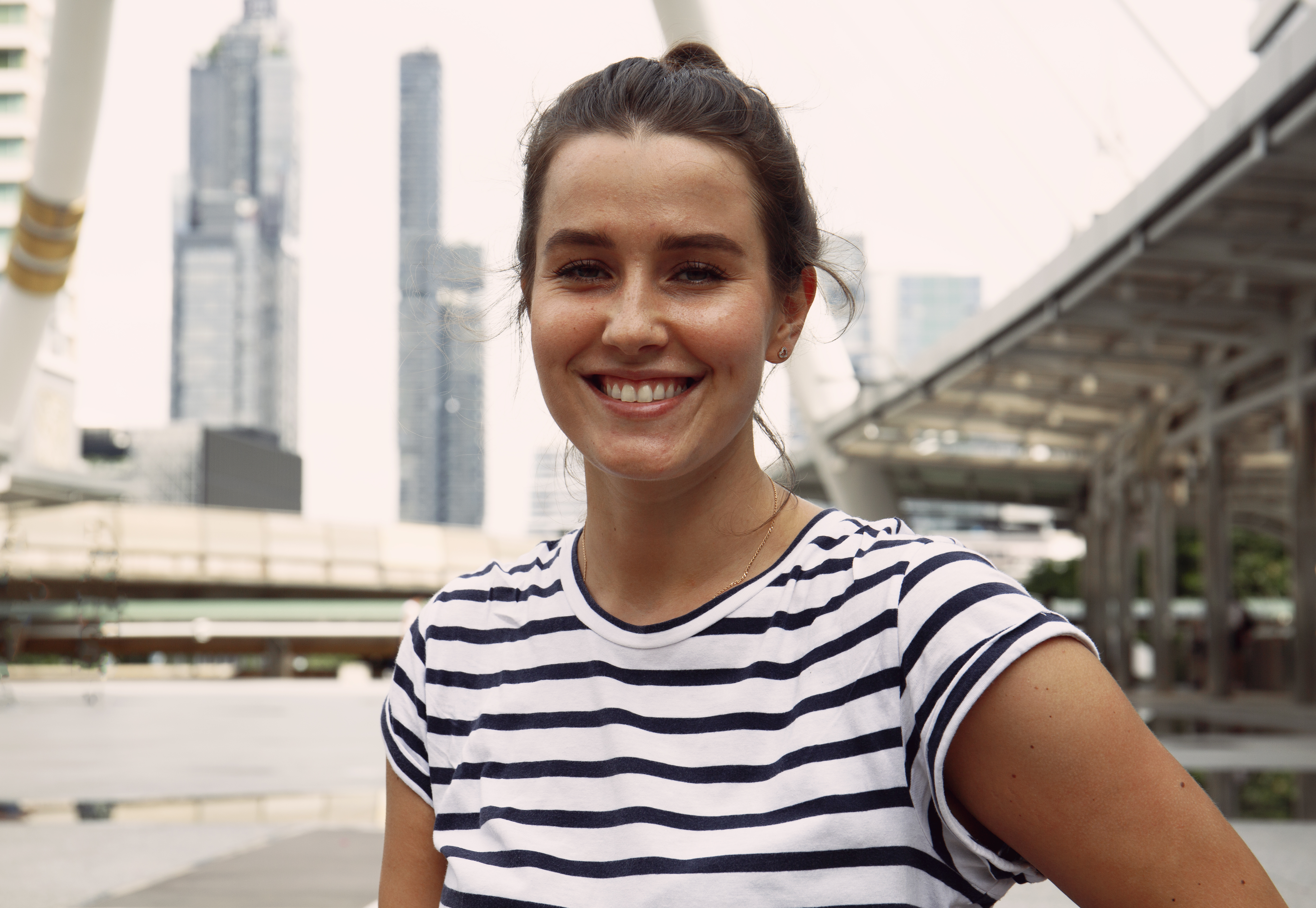 Smiling woman in a striped shirt, city backdrop
