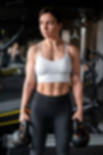 Sportlerin mit Kurzhanteln im Fitnessstudio