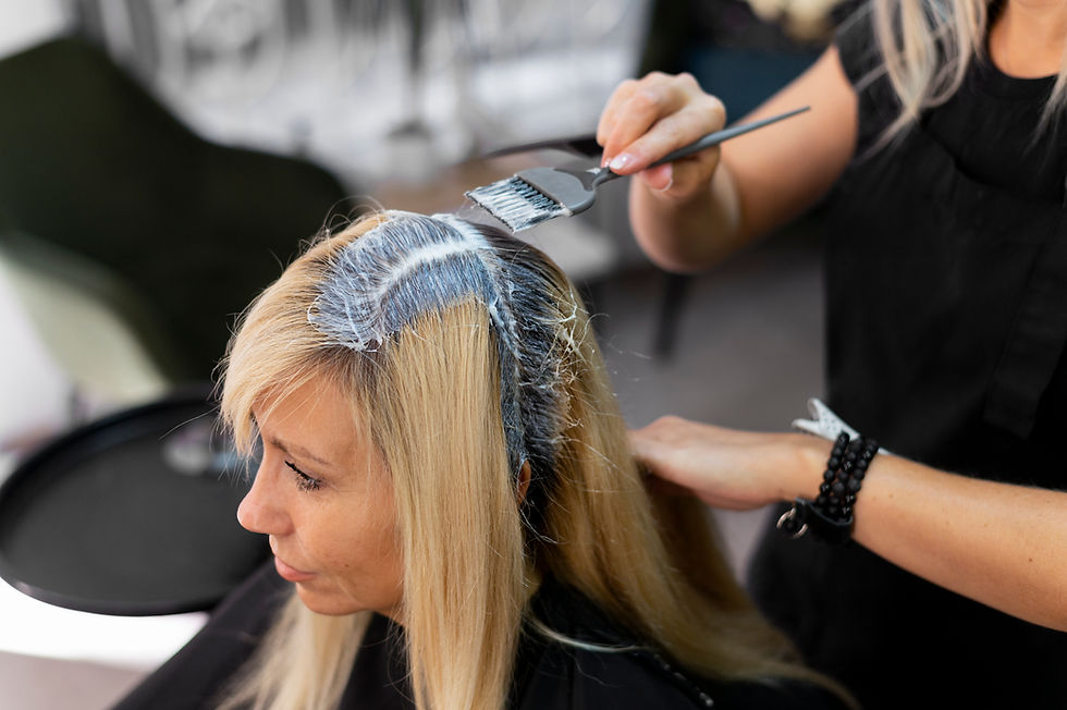 Friseurin trägt Blondierung auf