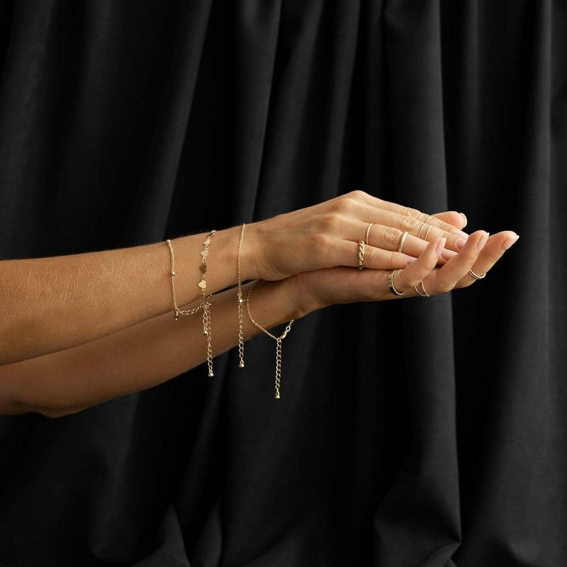 Elegante goldene Armbänder und Ringe an Frauenhänden