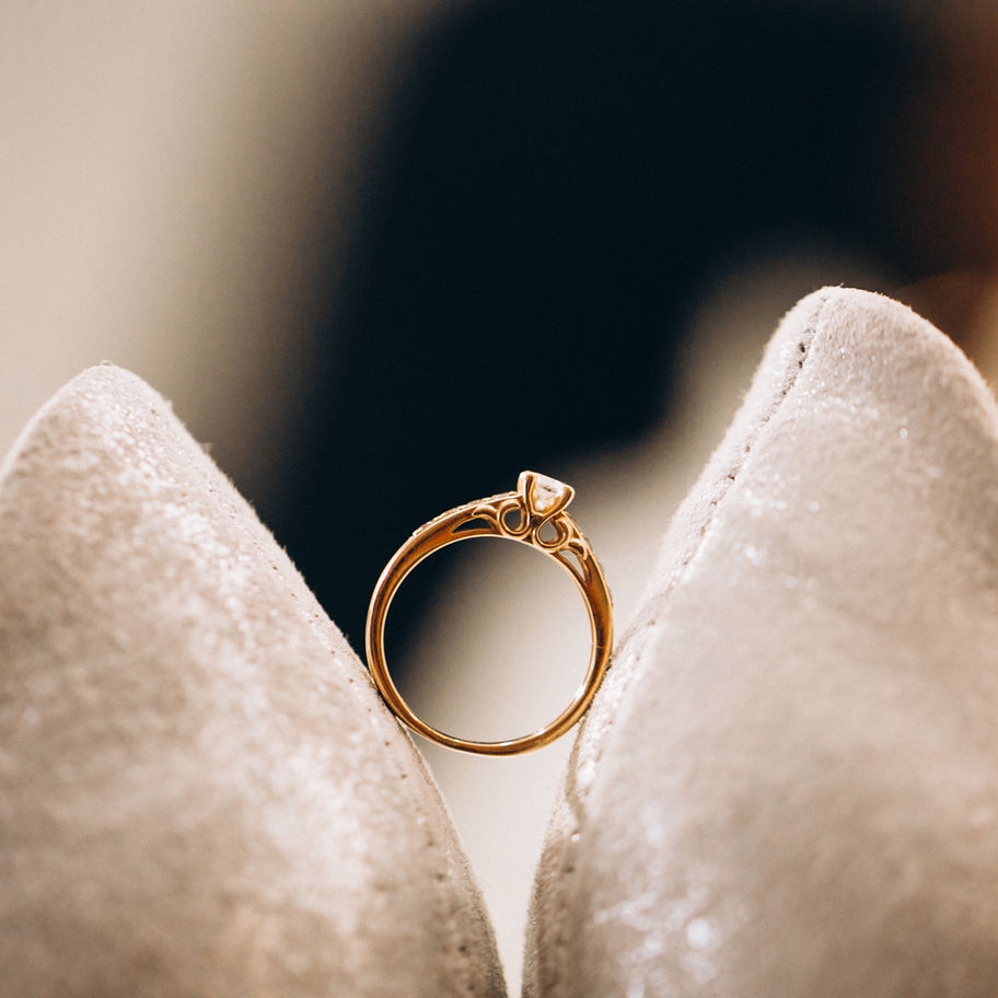 Verlobungsring auf beigefarbenen Hochzeitsschuhen