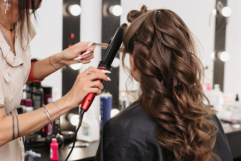 Friseurin stylt lange braune Locken mit Lockenstab
