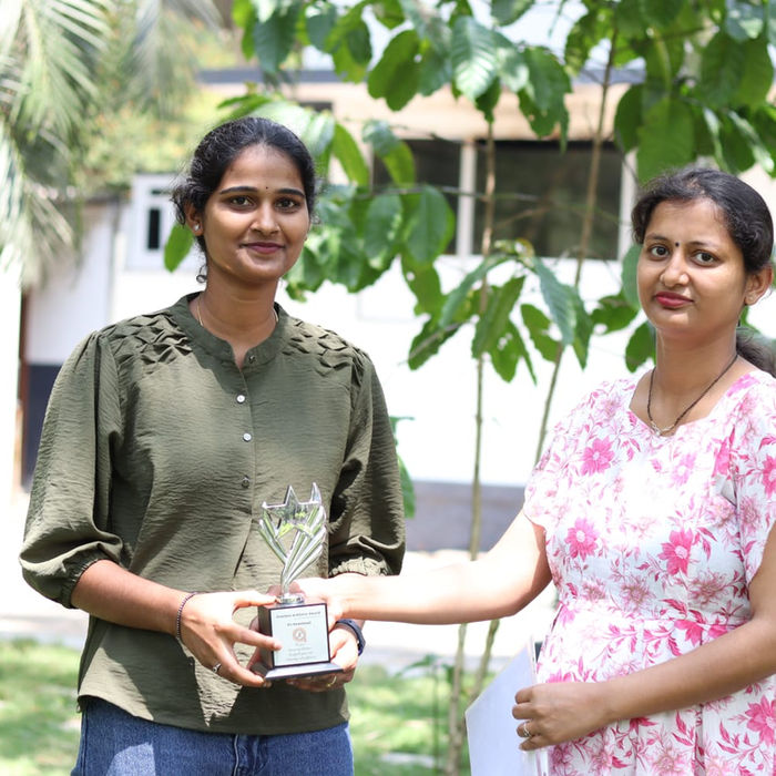 Gowthami and riya Mottana Prakash (Founder & CEO)standing outdoors, one receiving a trophy - Creative Digital Agency 